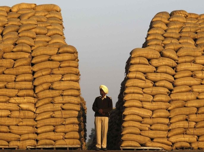 A watchman stands next to heaps of sacks filled with paddy at a wholesale grain market in the northern Indian city of Chandigarh November 15, 2014. India's inflation dropped to a new multi-year low in October, helped by slower annual rises in food and fuel prices, intensifying pressure on the central bank to cut interest rates to encourage spending and investment needed to boost growth. REUTERS/Ajay Verma (INDIA - Tags: BUSINESS COMMODITIES)